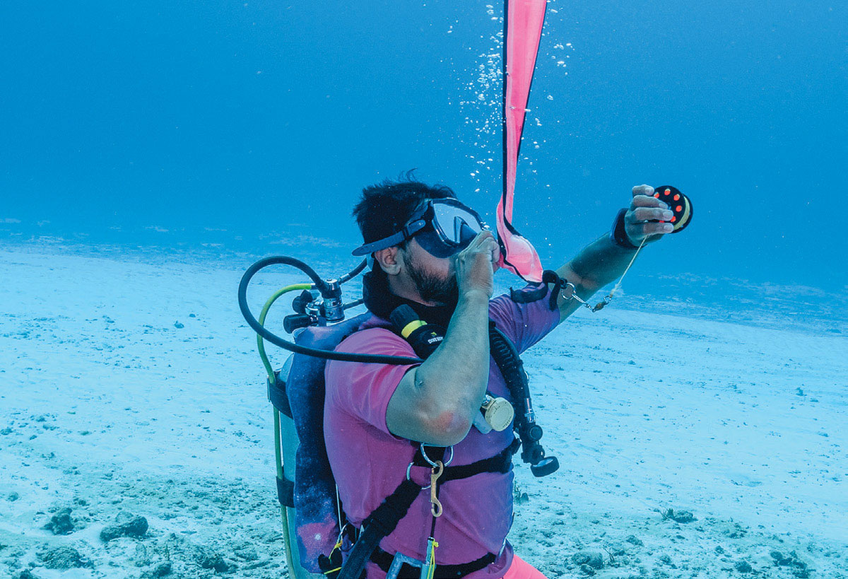 scuba diver inflating safety sausage